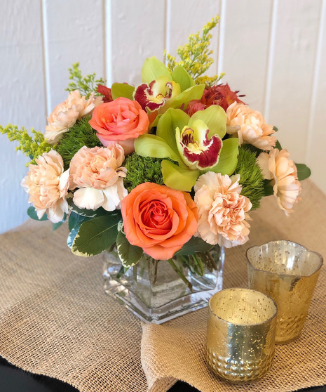 Peach, orange and green flowers in a clear glass vase